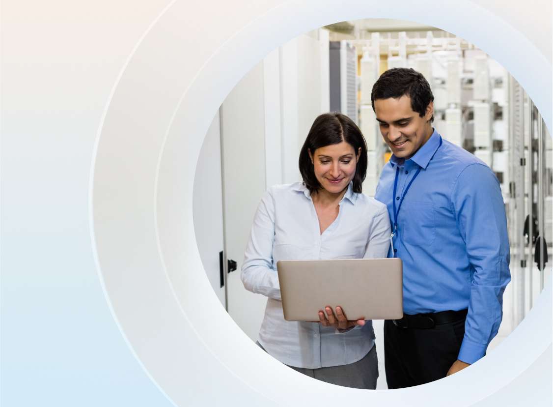 Two people standing in the IT server room looking at their laptop